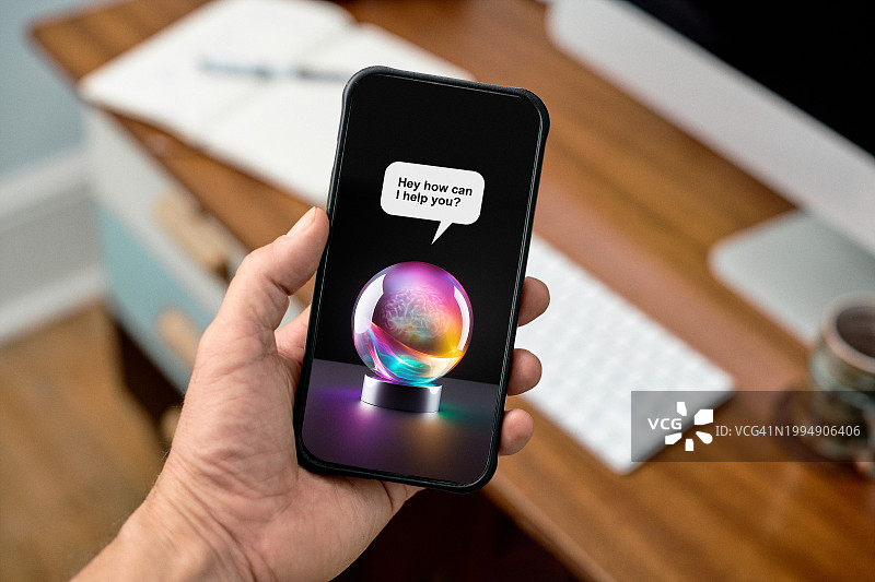 办公室场景：手机屏幕上以水晶球形式显示的AI聊天机器人图片素材