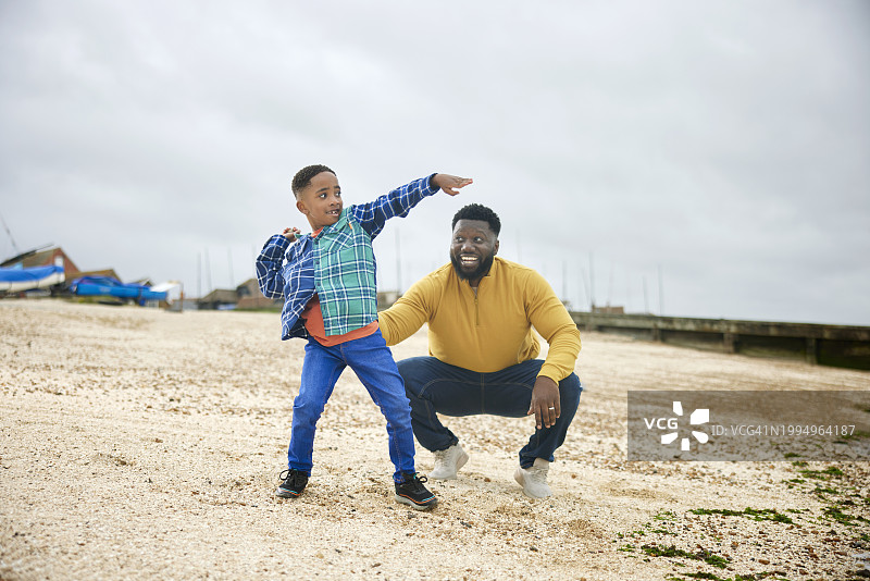 父子向海里扔石头的广阔镜头图片素材