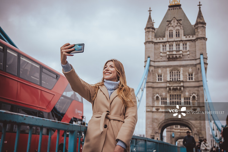 年轻金发女孩在伦敦标志性地标前观光，微笑着用手机自拍创意库存照片图片素材