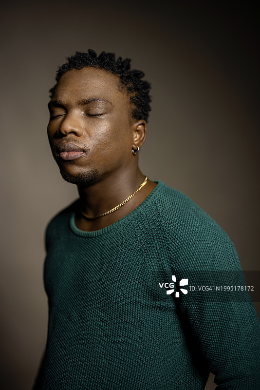 在工作室里闭着眼睛的年轻非洲男子图片素材