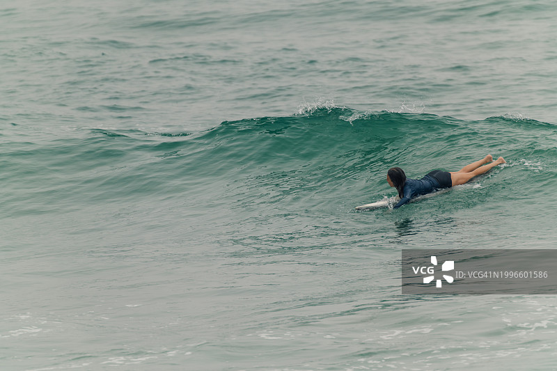 年轻冲浪女孩在海中冲浪图片素材