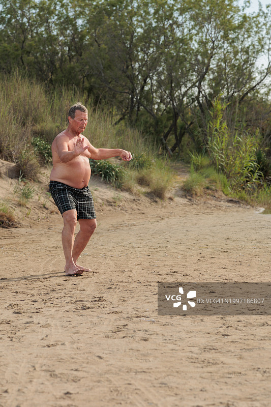 在海滩上度假打太极的老年男人图片素材