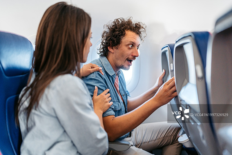 年轻女子在飞机上安慰惊恐发作的男友图片素材