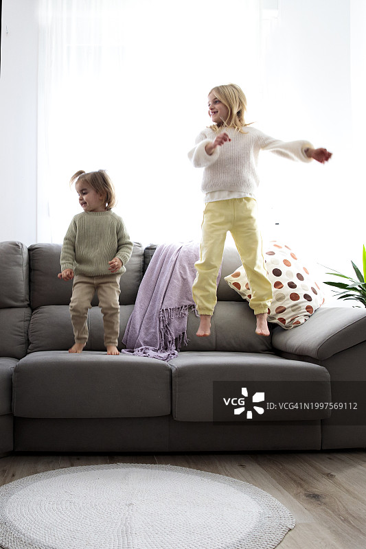 女孩们在家里沙发上跳跃图片素材