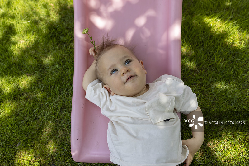 可爱的男婴躺在草地上享受阳光图片素材
