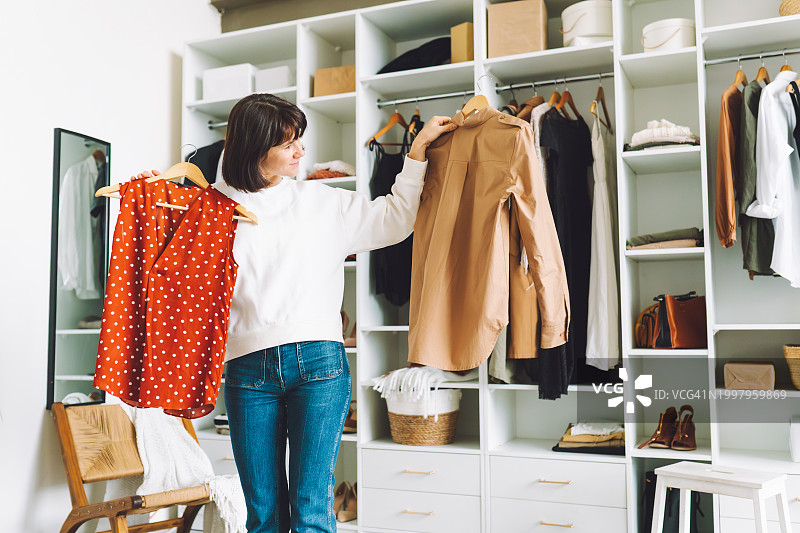 妇女在衣柜里选择衣服，为新的一天做准备图片素材