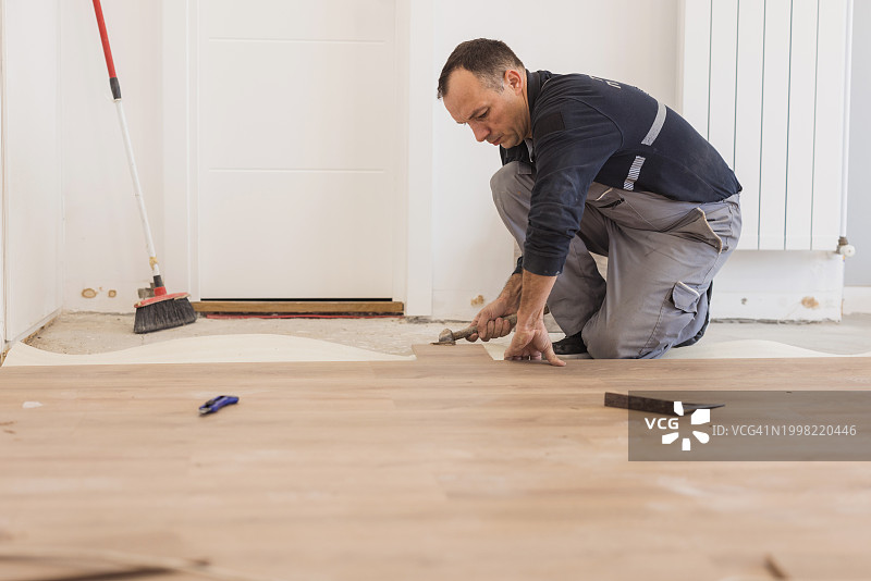 男人在铺设硬木地板砖时使用锤子图片素材