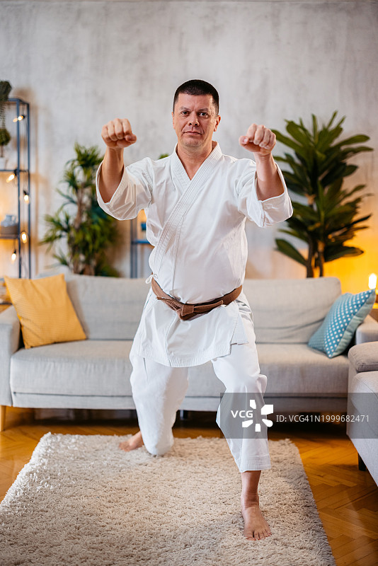 中年男人穿着白色和服在家练习空手道图片素材