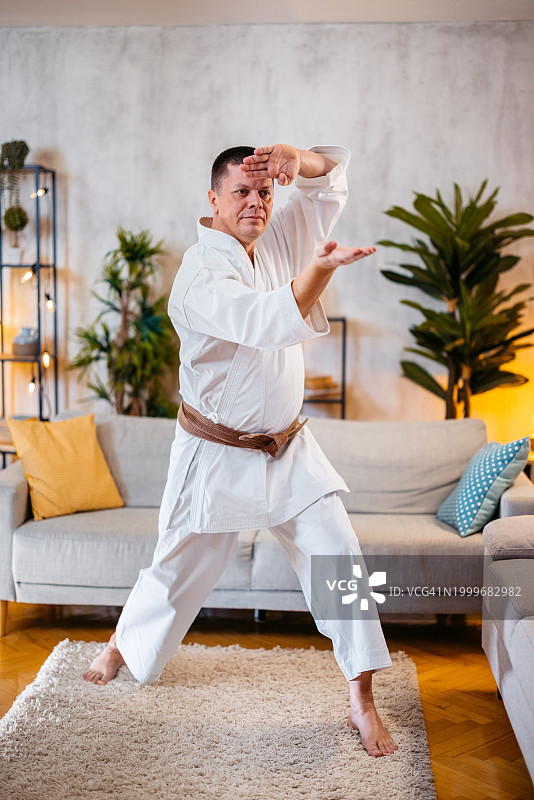 中年男人穿着白色和服在家练习空手道图片素材