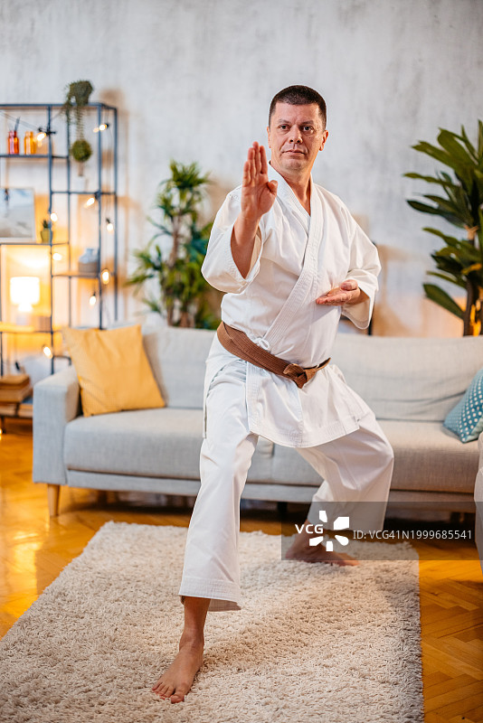 中年男人穿着白色和服在家练习空手道图片素材