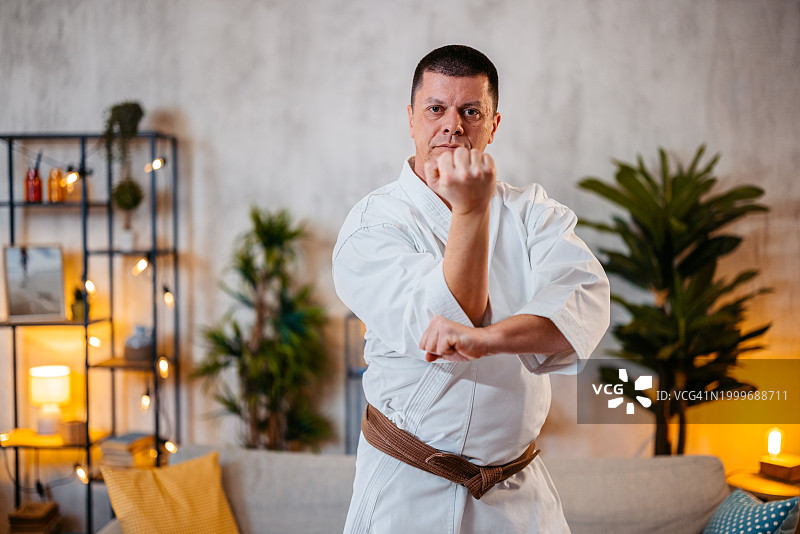 中年男人穿着白色和服在家练习空手道图片素材