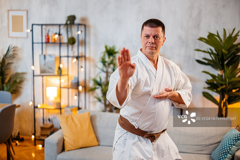 中年男人穿着白色和服在家练习空手道图片素材