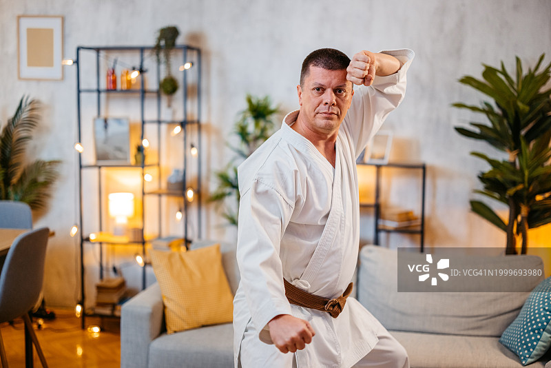 中年男人穿着白色和服在家练习空手道图片素材