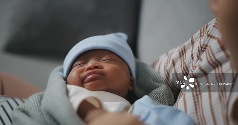 在母亲怀里睡觉的新生儿，小心地触摸着小胳膊图片素材