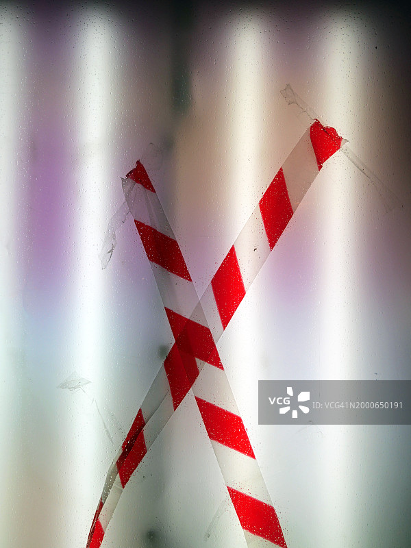 在比利时布鲁塞尔，白色和不透明的照明窗户上交叉的白色和红色警戒线。电灯。自然色和阴影。图片素材