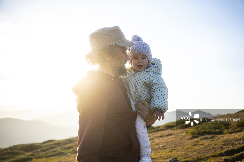 父亲和孩子在日落时于大自然中徒步旅行图片素材