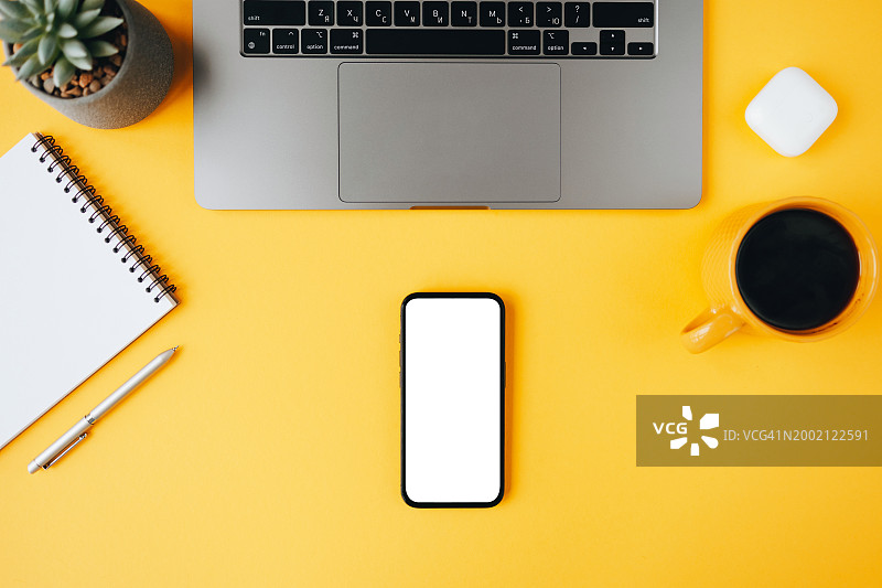 黄色背景上带有空白屏幕智能手机的整洁工作区顶视图图片素材