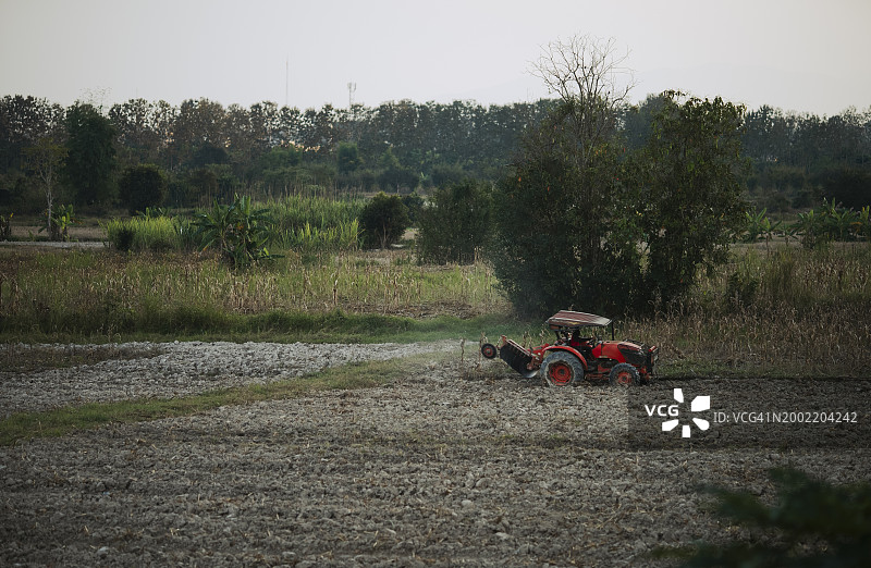 红色拖拉机在耕地中作业图片素材