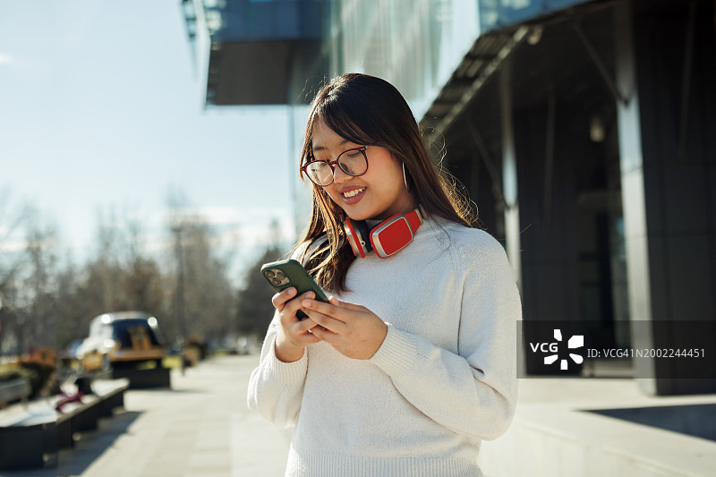 站在现代建筑前发短信的年轻漂亮女人图片素材