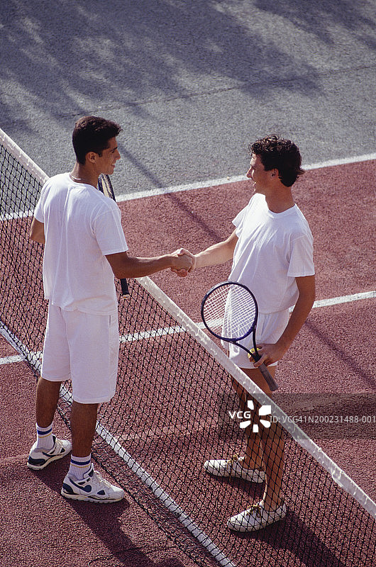 两个年轻人在网球场上握手（高角度）图片素材