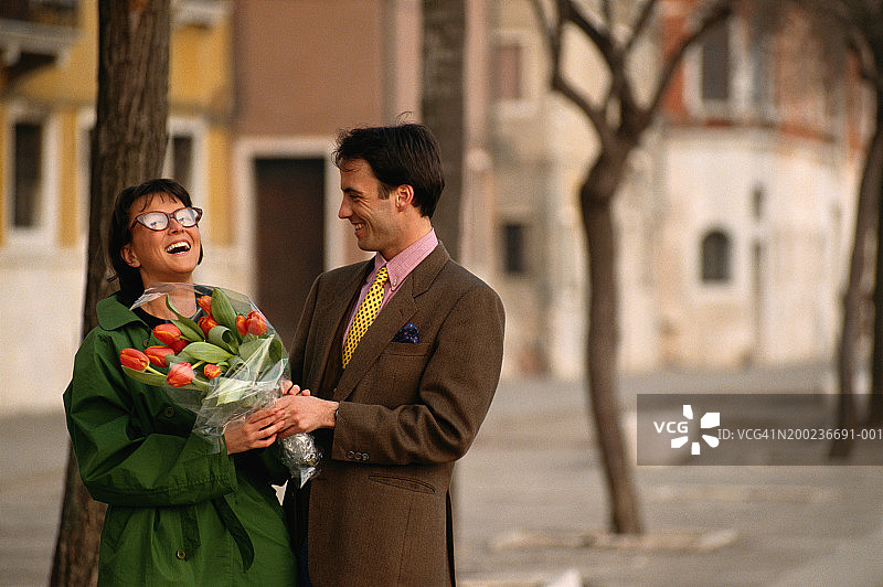 中年夫妇拿着玫瑰花，开怀大笑图片素材