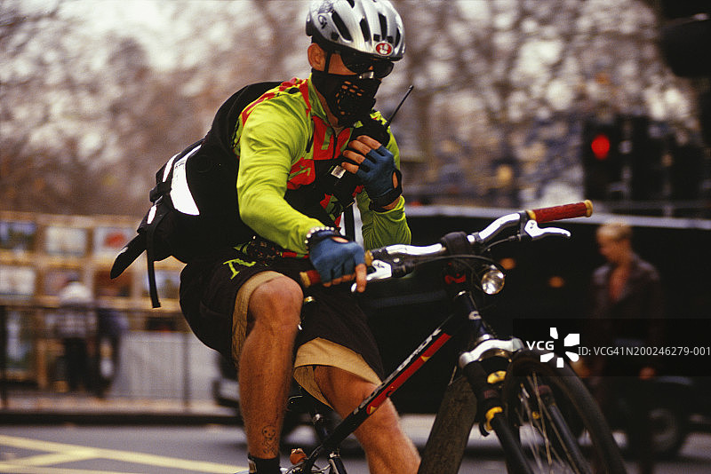 骑自行车的人在繁忙的街道上使用对讲机图片素材