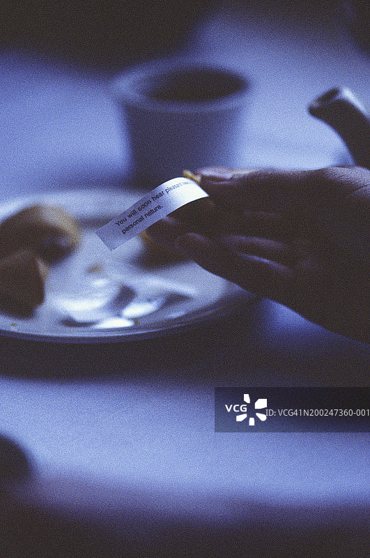 女人拿着幸运饼干里的纸条，手部特写图片素材