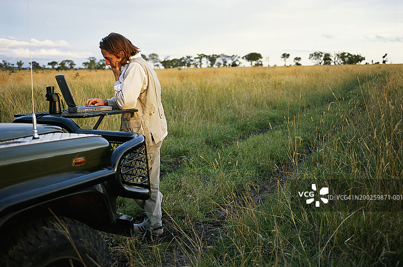 男人在越野车前使用笔记本电脑图片素材