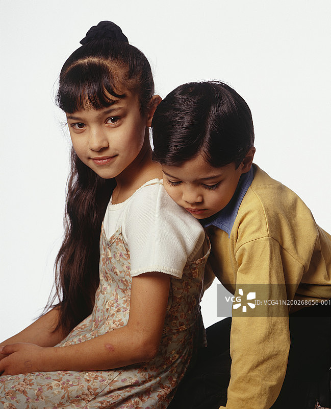 哥哥靠在妹妹的肩膀上，在影棚里摆姿势，肖像照图片素材