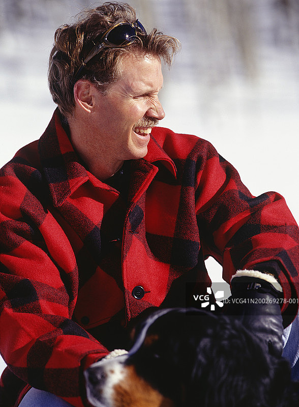 男子在雪地里和狗一起蹲着图片素材