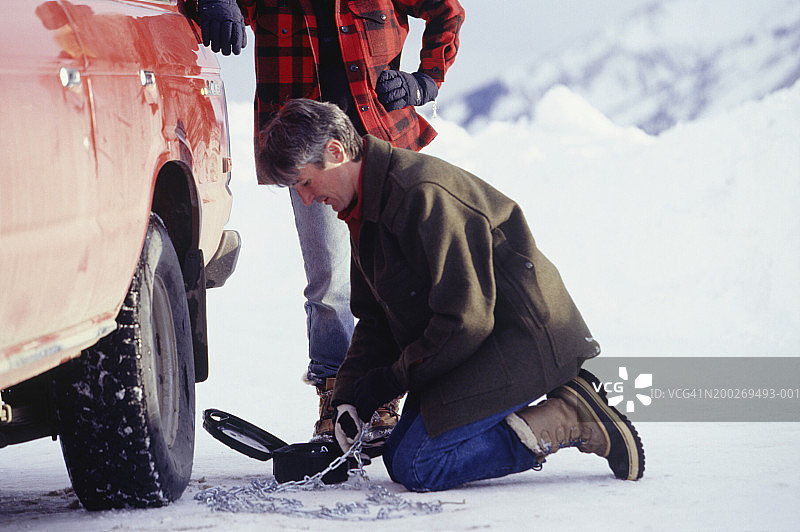 男人在山区为汽车轮胎安装防滑链图片素材