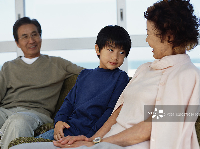 和祖父母坐在沙发上的男孩（5-7岁）图片素材