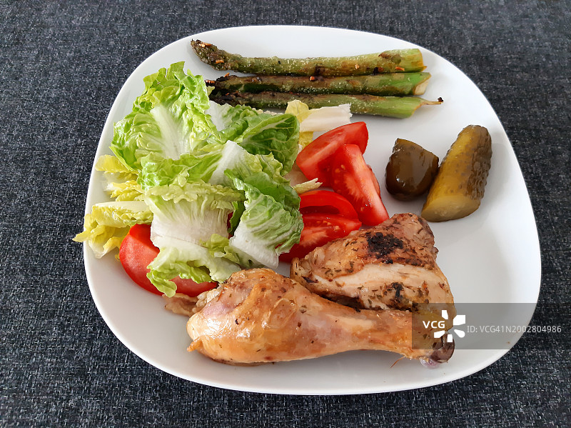 自制烤鸡腿配烤芦笋、绿色沙拉、番茄片和腌黄瓜图片素材