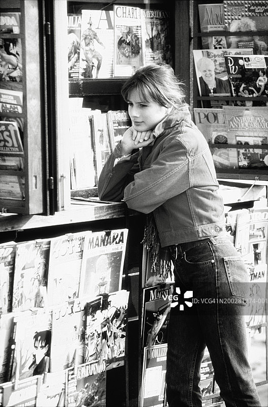 站在杂志摊旁的年轻女人图片素材