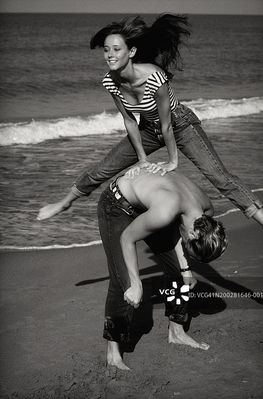 女人在海滩上跳过男人图片素材