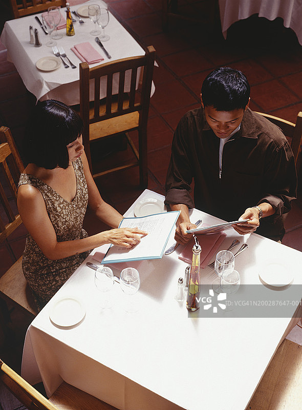 在餐厅查看菜单的年轻夫妇，仰视图片素材