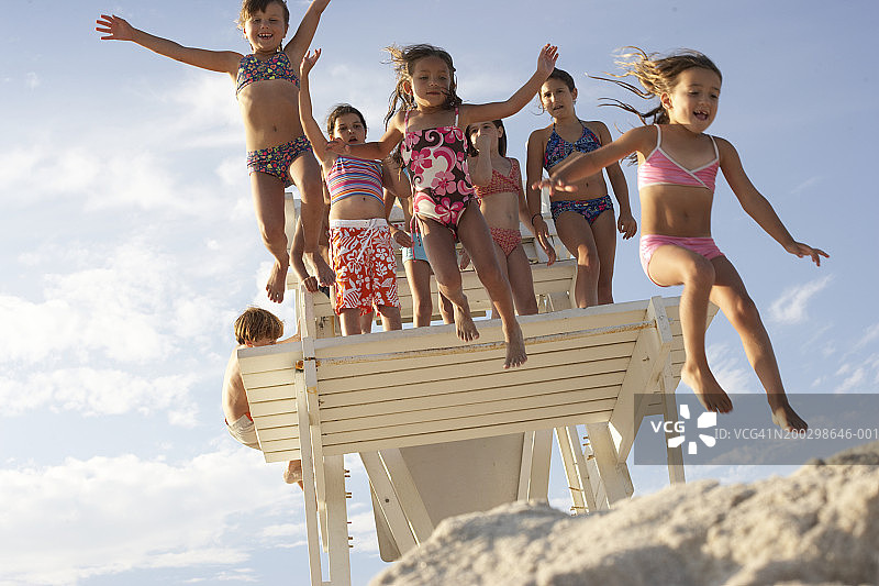 一群5-11岁的孩子从救生员平台上跳下图片素材