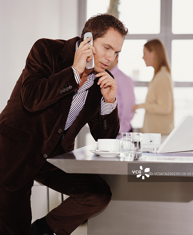 使用手机的商人，同事在背景中图片素材