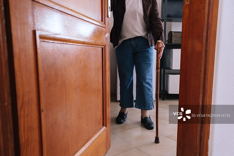 拄着拐杖进入木门的年长者图片素材