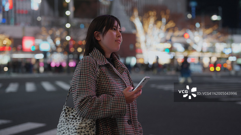 夜晚女人在城市里使用智能手机图片素材