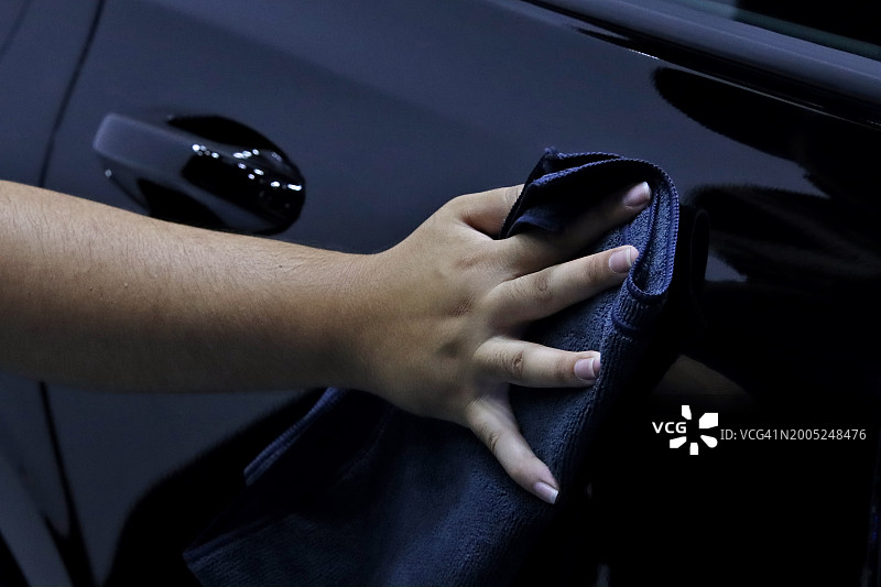 男人用超细纤维布擦拭汽车，汽车清洁概念图片素材