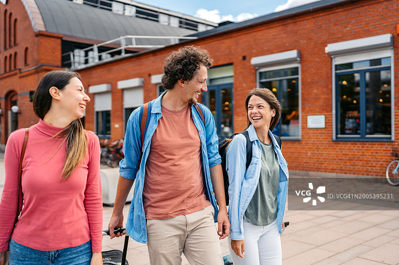 三名游客拖着行李走在马尔默市图片素材