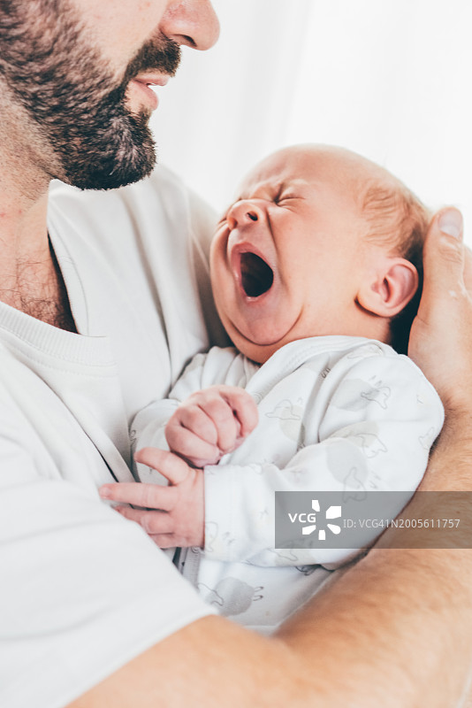 父亲在家中抱着哭泣的孩子图片素材