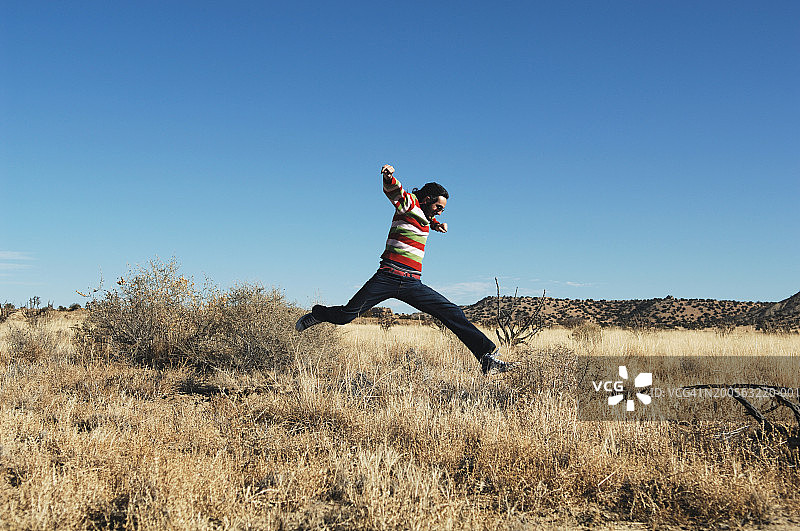 在干旱景观中跳跃的年轻男人图片素材