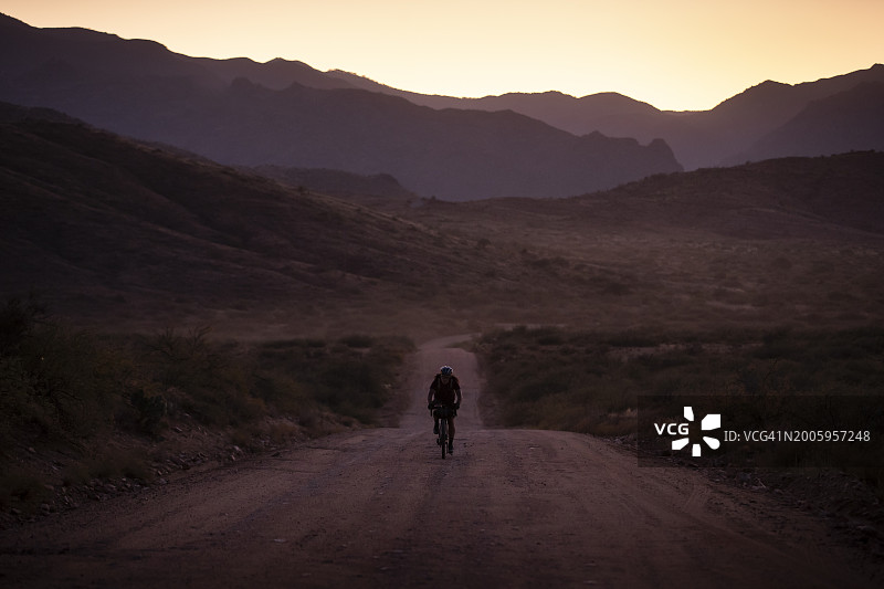 一名骑自行车的人骑着配备露营装备的砾石公路自行车，从弗拉格斯塔夫到菲尼克斯，途经塞多纳和亚利桑那州黑峡谷图片素材