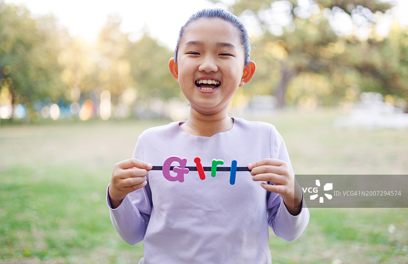 手拿"GIRL"字样的小女孩图片素材