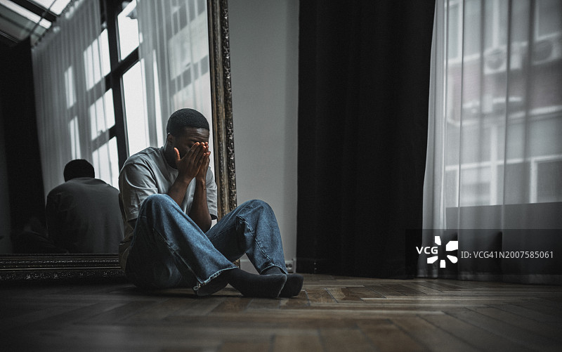 沮丧、孤独和情绪压力时刻。年轻黑人男子坐在地上，看起来非常沮丧和有压力图片素材