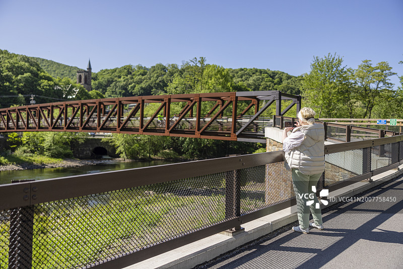 游客拍摄宾夕法尼亚州吉姆索普河畔风光，女士在桥上拍摄地标图片素材