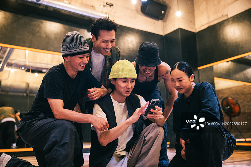 朋友们在智能手机上看嘻哈社交媒体短片图片素材