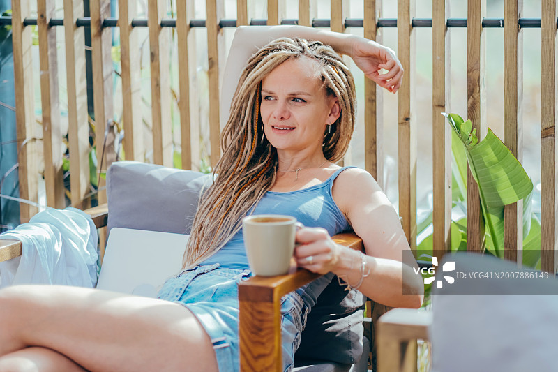 惬意的阳光午后，享受咖啡的脏辫美女图片素材